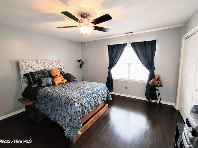 bedroom featuring baseboards, a closet, visible vents, and wood finished floors