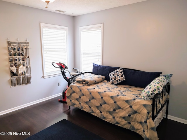 bedroom featuring visible vents, baseboards, and wood finished floors