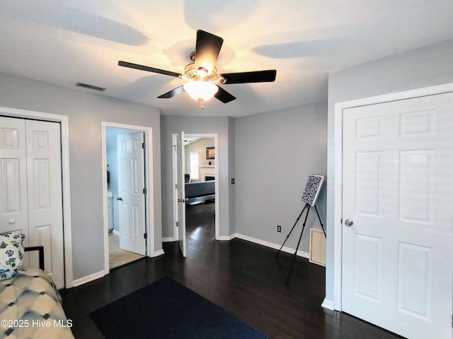 bedroom featuring a textured ceiling, dark wood-type flooring, visible vents, and baseboards