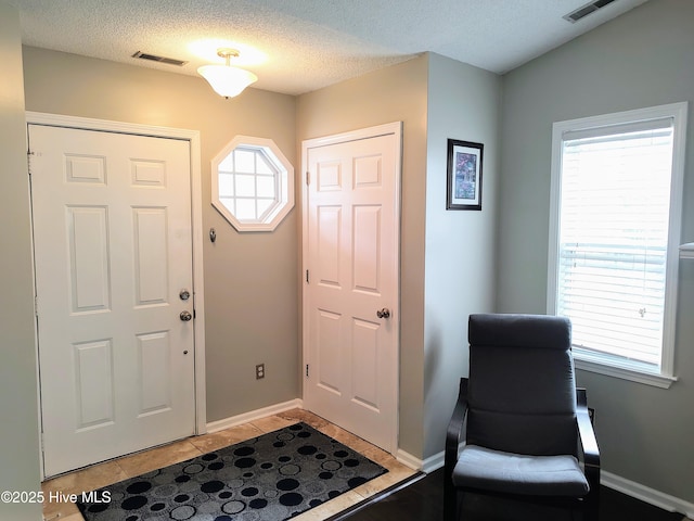 entrance foyer featuring a healthy amount of sunlight, light tile patterned floors, and visible vents