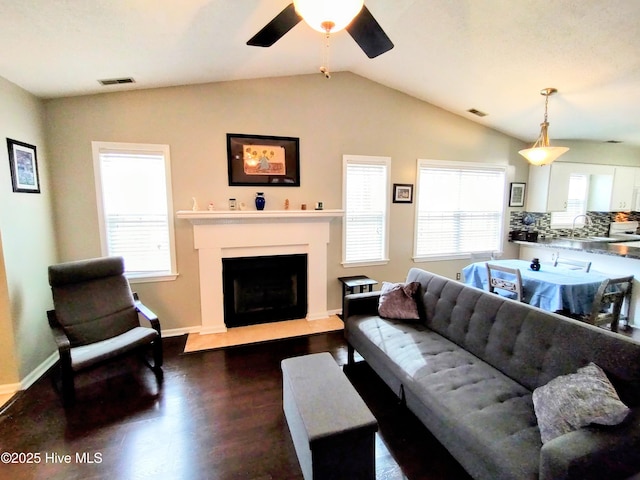 living area with lofted ceiling, dark wood-type flooring, a fireplace, and visible vents