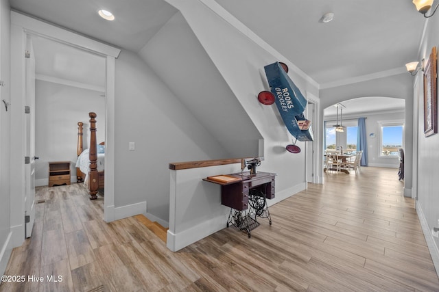 hall with baseboards, ornamental molding, wood finished floors, recessed lighting, and arched walkways