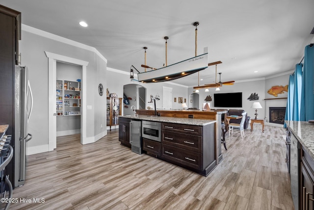 kitchen featuring open floor plan, arched walkways, stainless steel appliances, and crown molding