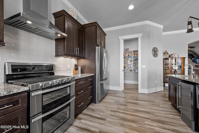 kitchen with beverage cooler, wall chimney range hood, light stone countertops, and appliances with stainless steel finishes