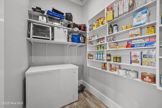 laundry room featuring baseboards and wood finished floors
