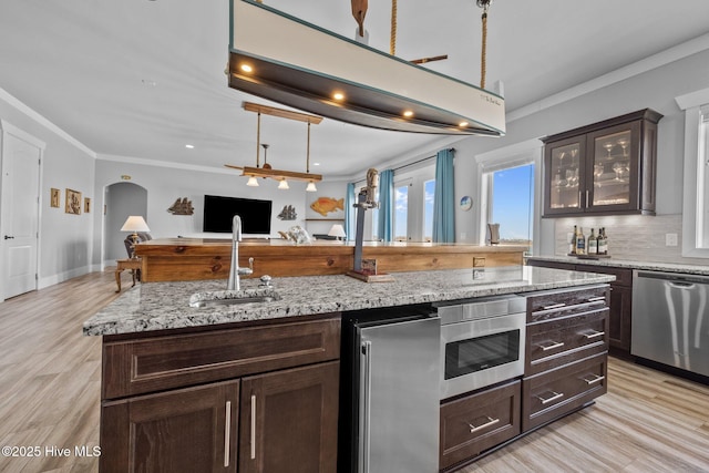 kitchen with a sink, appliances with stainless steel finishes, open floor plan, decorative backsplash, and dark brown cabinets