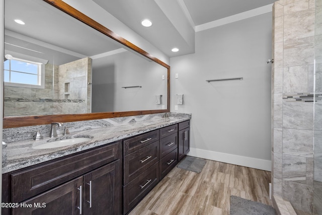 full bathroom featuring double vanity, a sink, baseboards, and wood finished floors