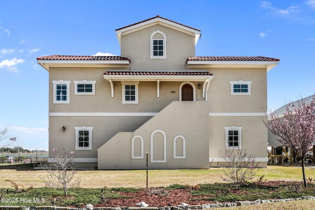 mediterranean / spanish-style home featuring a front lawn, stucco siding, and a tiled roof