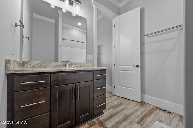full bath featuring vanity, visible vents, baseboards, and wood finished floors
