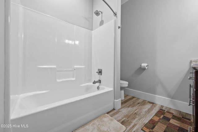 full bath featuring toilet, shower / washtub combination, baseboards, and wood finished floors