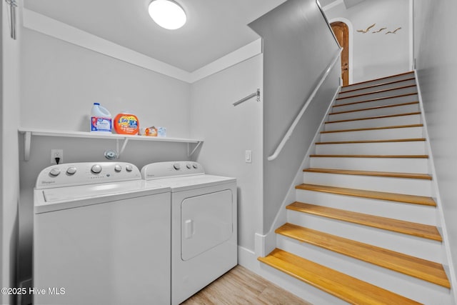 clothes washing area with washing machine and dryer and light wood-style floors