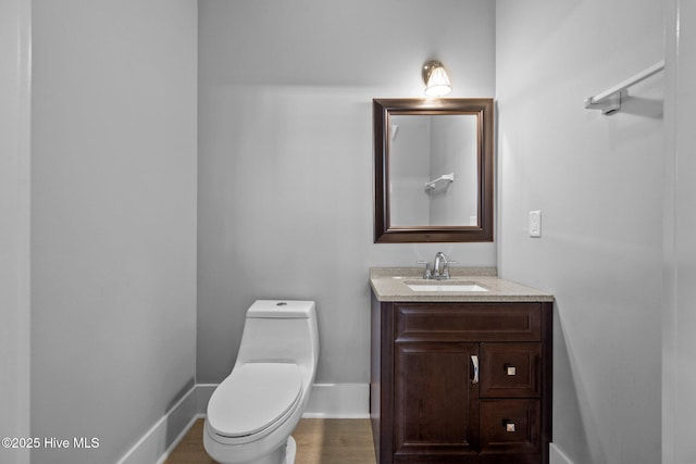 bathroom with baseboards, wood finished floors, toilet, and vanity