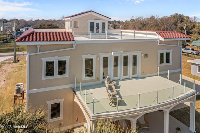 rear view of property featuring a tile roof, stucco siding, and central air condition unit
