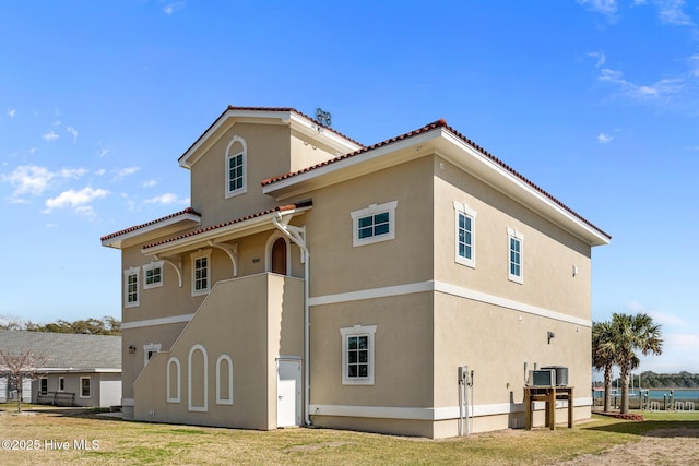 exterior space with stucco siding, a tiled roof, and central AC