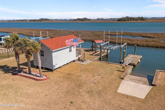 view of dock featuring a water view, boat lift, and a yard