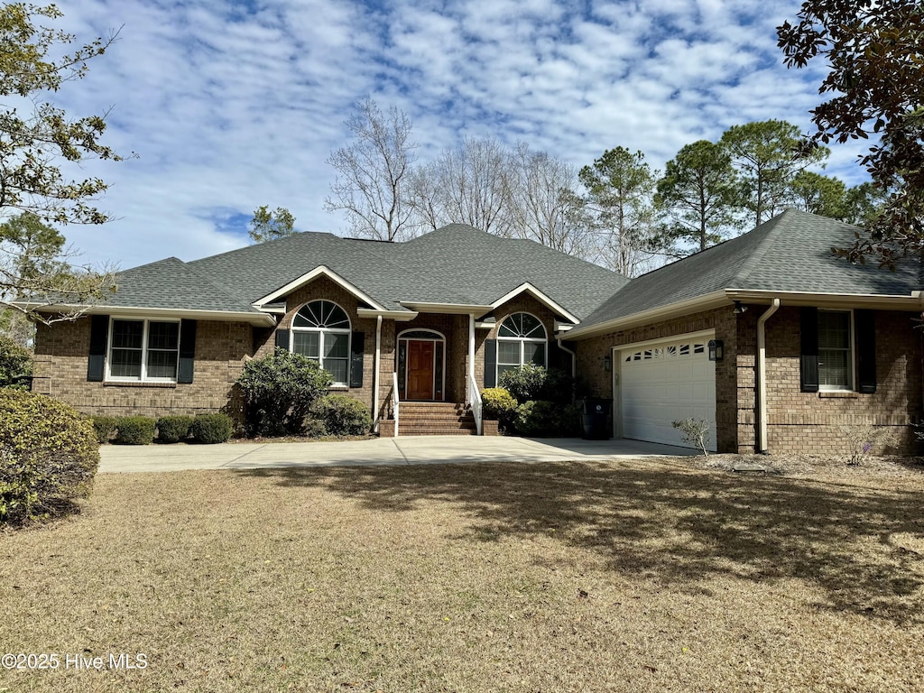 234 Crooked Gulley Cir, Sunset Beach, NC 28468 - ranch-style house with a garage, brick siding, driveway, and a shingled roof