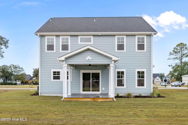 rear view of house with ceiling fan and a yard