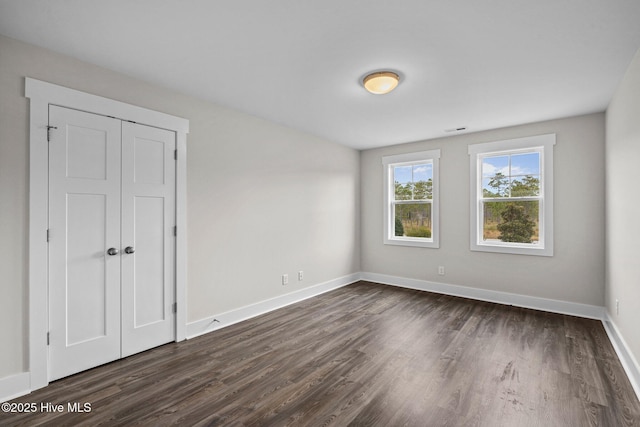 interior space with dark wood-style floors, a closet, visible vents, and baseboards