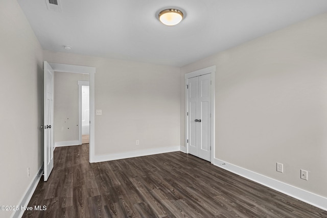 spare room with dark wood-style floors, visible vents, and baseboards