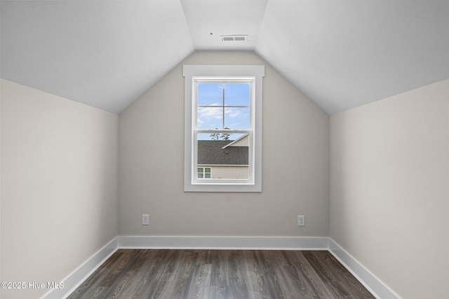 additional living space featuring lofted ceiling, baseboards, visible vents, and dark wood finished floors