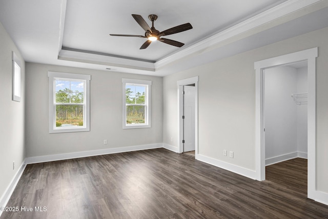 unfurnished bedroom featuring dark wood-type flooring, a raised ceiling, and baseboards