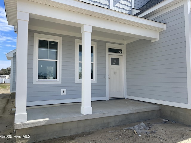 entrance to property featuring a porch and roof with shingles