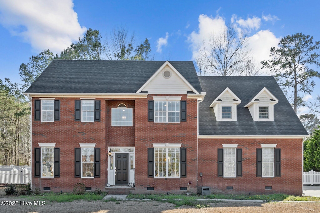 view of front facade featuring crawl space, fence, brick siding, and roof with shingles