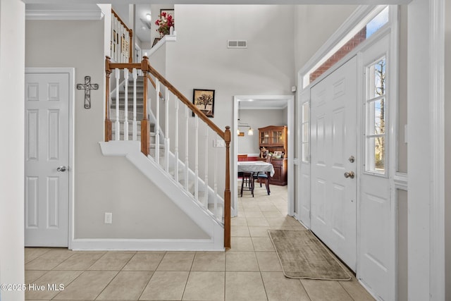 entrance foyer with tile patterned floors, visible vents, stairs, and crown molding