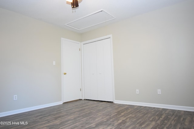 unfurnished bedroom featuring attic access, a closet, baseboards, and wood finished floors