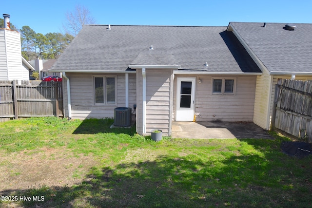 back of property featuring roof with shingles, a patio, a lawn, central AC unit, and fence