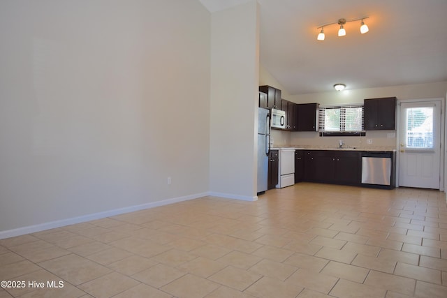 kitchen featuring lofted ceiling, a sink, baseboards, light countertops, and appliances with stainless steel finishes