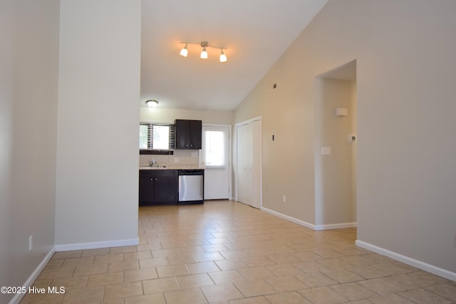 kitchen featuring light countertops, baseboards, vaulted ceiling, and stainless steel dishwasher