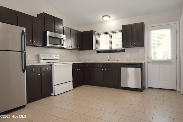 kitchen featuring vaulted ceiling, light countertops, appliances with stainless steel finishes, and a sink