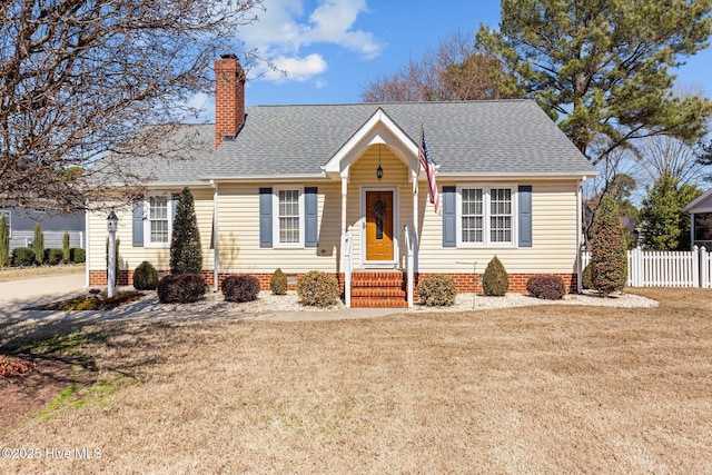 view of front of property featuring a shingled roof, a chimney, a front yard, and fence