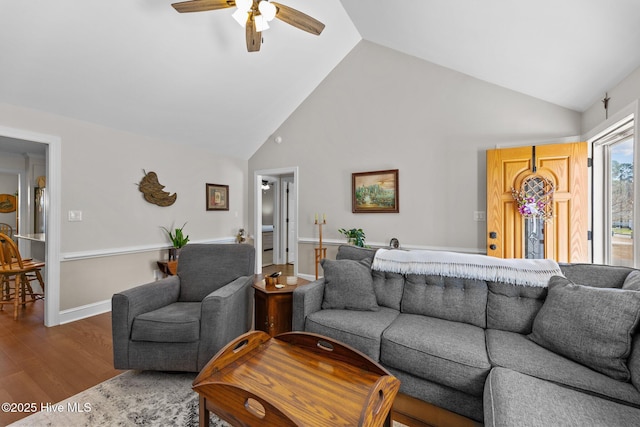 living room featuring baseboards, ceiling fan, high vaulted ceiling, and wood finished floors