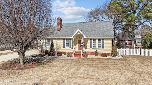 cape cod-style house with a shingled roof, a chimney, fence, and a front yard