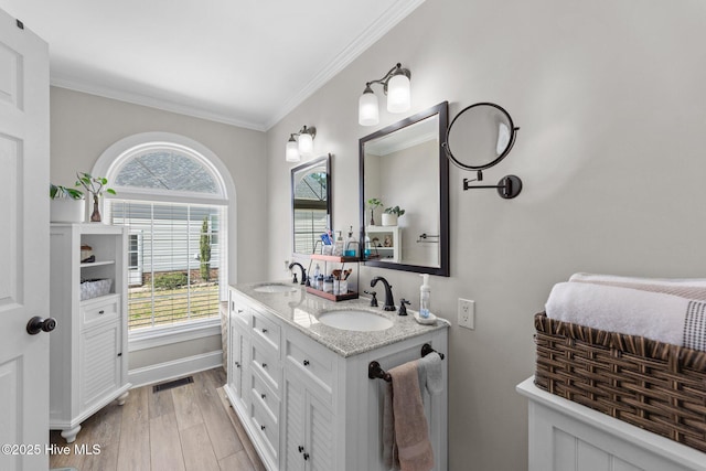 bathroom featuring ornamental molding, double vanity, a sink, and wood finished floors