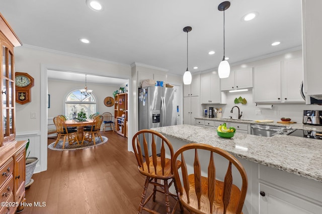 kitchen with a breakfast bar area, stainless steel appliances, dark wood-type flooring, white cabinets, and crown molding