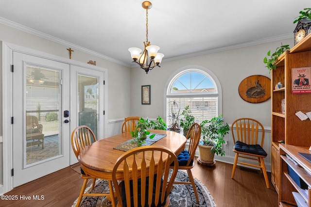 dining space featuring a notable chandelier, ornamental molding, wood finished floors, and french doors