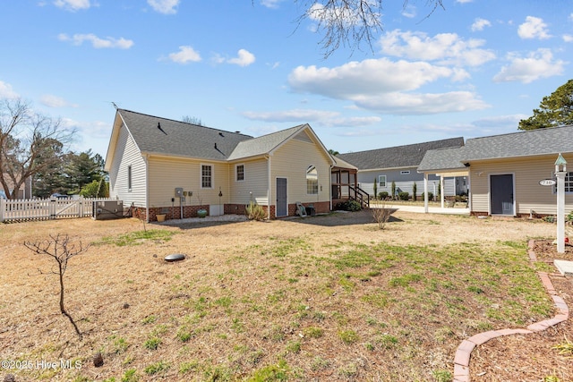 back of property with a gate, fence, and a lawn