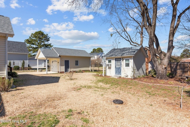 back of house with a garage, an outbuilding, fence, and a lawn