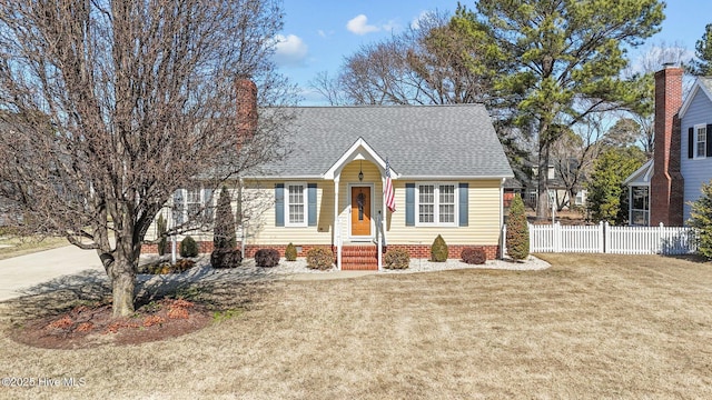 view of front of home featuring roof with shingles, fence, and a front lawn