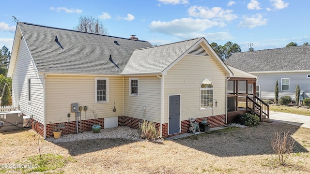 rear view of property with crawl space, roof with shingles, and a chimney