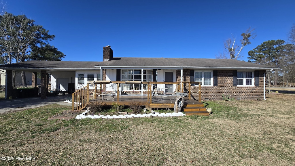 ranch-style house featuring brick siding, a chimney, an attached carport, driveway, and a front lawn