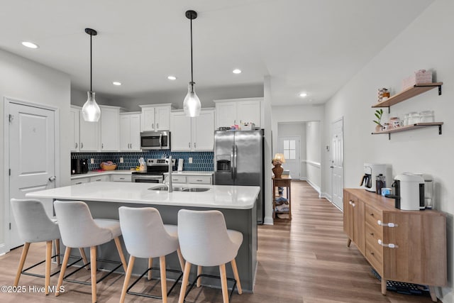 kitchen with tasteful backsplash, light countertops, appliances with stainless steel finishes, light wood-style floors, and white cabinetry