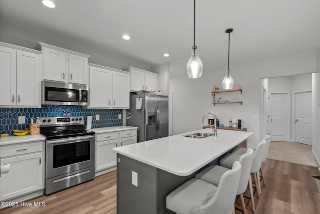 kitchen with decorative backsplash, stainless steel appliances, a sink, and wood finished floors