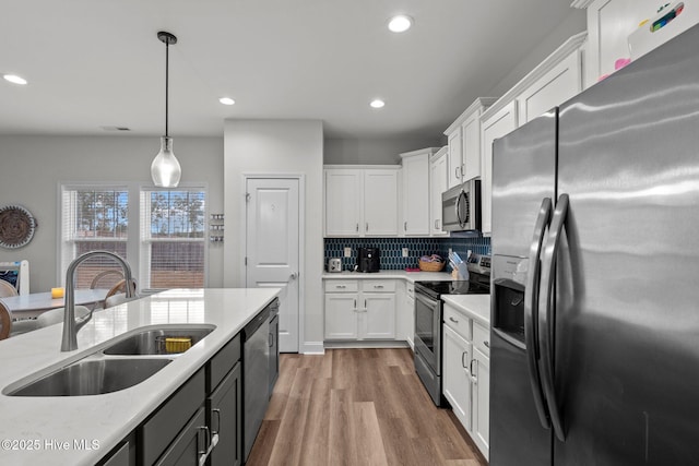 kitchen with white cabinets, light wood-style floors, stainless steel appliances, and a sink