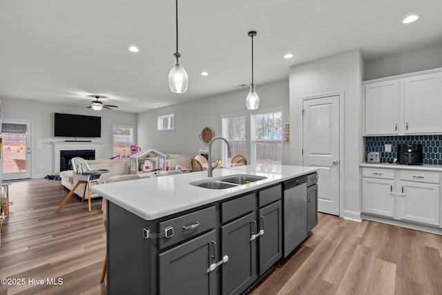 kitchen featuring white cabinets, a sink, light wood finished floors, and stainless steel dishwasher