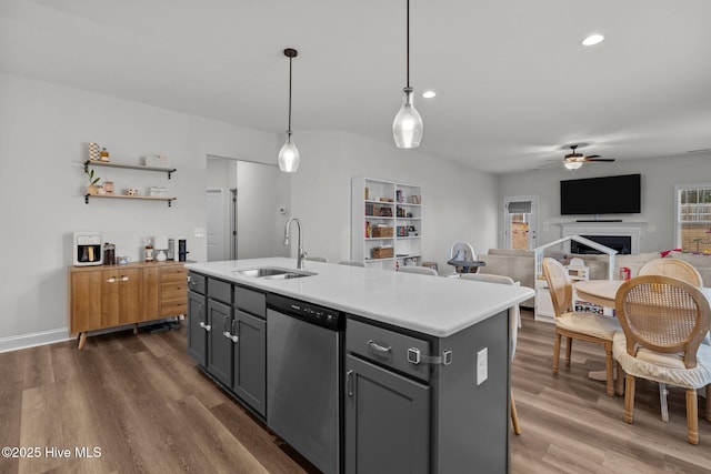 kitchen featuring dark wood-type flooring, decorative light fixtures, light countertops, stainless steel dishwasher, and a sink