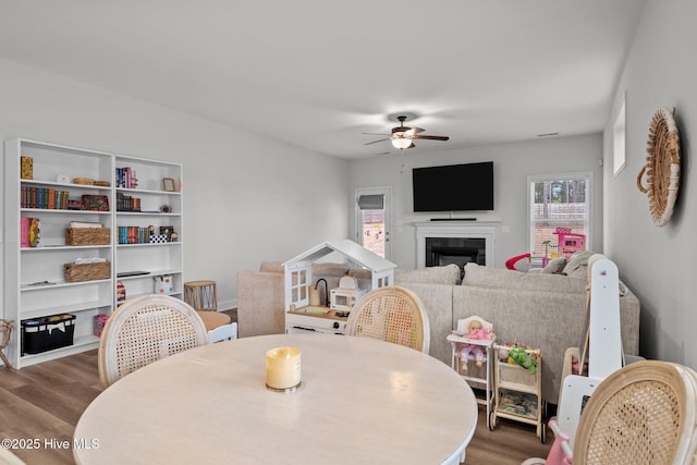 dining room featuring ceiling fan, a fireplace, and wood finished floors